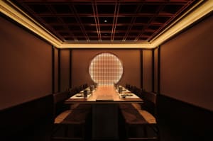 Elegant dining space with wooden walls and ceiling, featuring tables and chairs, and traditional Asian design elements