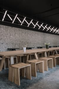 Warm and inviting restaurant interior with a large dining table and wooden benches, surrounded by chairs
