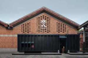 Exterior view of a modern Asian building with a brick facade, featuring a unique design and traditional elements