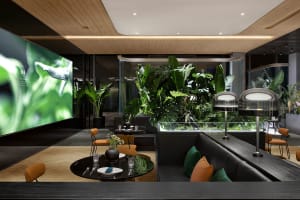 A modern living area with a large window, a couch, chairs, potted plants, and a dining table, well-lit and inviting