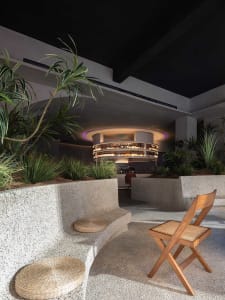 A casual indoor space with a couch, two chairs, and scattered bottles, creating a relaxed atmosphere for conversation and socializing