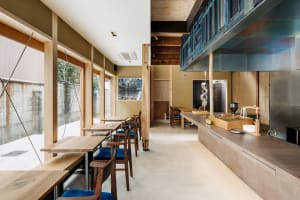 Warm and inviting open kitchen with wooden floors and walls, featuring a dining table, chairs, kitchen utensils, and ample seating options