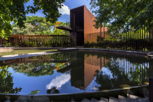 A rendered image of a pool surrounded by a fence, set in front of a brown building with trees nearby, creating a relaxing atmosphere