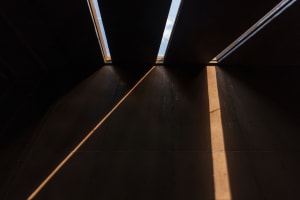 A spacious cafe interior with a large window allowing sunlight to enter, casting shadows on the walls and creating a sense of depth and dimension
