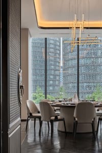 Sophisticated dining space with a large table set for a meal, surrounded by chairs and wine glasses