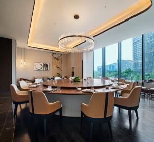 Sophisticated dining area with a round table, set with wine glasses, cups, and vases, surrounded by chairs and bottles