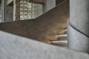 A modern staircase with metal railings in a well-lit stairwell, possibly in a museum or similar establishment