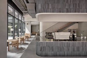 Modern restaurant kitchen with a large countertop island, sink, coffee maker, and dining table with chairs