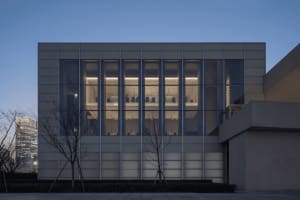 A concrete building with large windows on each side, allowing natural light to enter and creating a bright and inviting environment