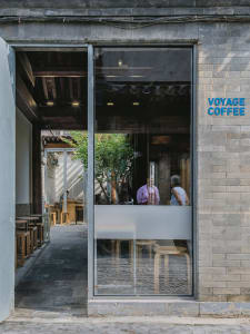 A cozy coffee shop with a brick wall, tables, chairs, and people enjoying a relaxed atmosphere