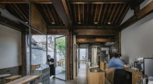 A warm and inviting restaurant interior with wooden floors and walls, featuring dining tables and chairs, and natural lighting