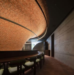 Cozy dining area with a brick wall, wooden table, and chairs, creating a warm and inviting atmosphere