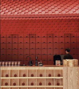 A casual kitchen scene with a red accent wall, wooden countertop, and various household items on display