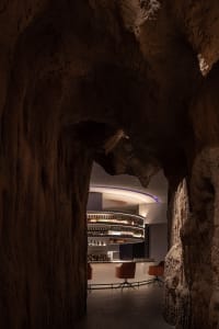Underground bar with a spiral staircase, circular bar area, and cozy seating options