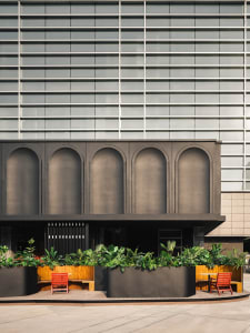 Modern building with a black facade featuring arches, two chairs placed in front, in a minimalist setting