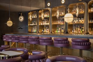 Inviting bar area with a long wooden counter, multiple stools, and bottles displayed behind the counter