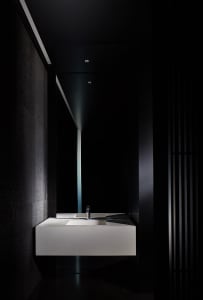 Modern bathroom with a white marble sink, black wall, and two bottles near the sink