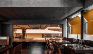 Elegant dining space with wooden tables, multiple chairs, and various table settings, illuminated by natural light