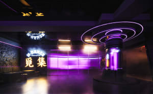 A surreal cityscape with a large purple structure surrounded by smaller purple objects, set against a dreamlike atmosphere