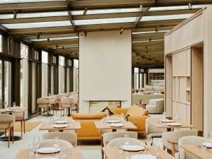 Warm and inviting restaurant interior with wooden floors and walls, featuring multiple dining tables and chairs