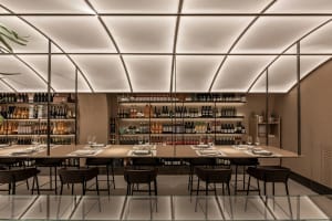 Elegant dining space with multiple tables, chairs, and wine bottles displayed on surfaces, creating a sophisticated ambiance
