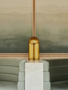 A luxurious living area with a couch in front of a wall featuring two large golden vases on a marble table, creating a comfortable seating space