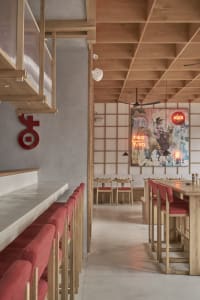 Empty restaurant with wooden floors and walls, featuring chairs around dining tables in a welcoming atmosphere