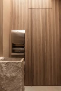 Bathroom with a sink, toilet paper dispenser, and wooden wall