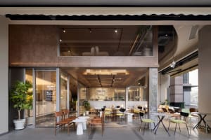 A well-lit restaurant interior with tables, chairs, potted plants, and decorative elements, creating a warm and inviting atmosphere
