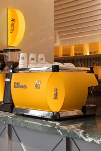 A coffee shop interior with yellow coffee makers and cups on display, creating an inviting atmosphere