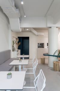 Modern restaurant interior with white walls, tables, and chairs, featuring a clean and inviting atmosphere with a focus on functionality and aesthetics