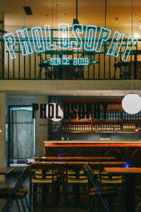 A restaurant interior with a bar area and dining tables, featuring a warm and inviting atmosphere with bottles on the counter and chairs around the tables