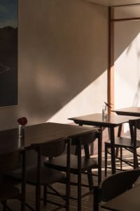 A warm and inviting dining area with multiple tables and chairs, a vase on one table, and a comfortable atmosphere