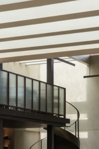A spiral staircase made of wood in a white-walled stairwell, conveying a sense of openness and simplicity