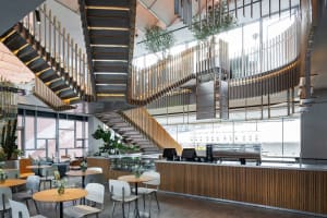Open restaurant interior with a wooden staircase, multiple dining tables, and comfortable seating