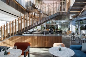 Open dining space with wood flooring, multiple tables, chairs, and potted plants, creating a modern and inviting atmosphere