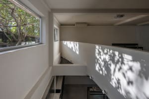 A dimly lit interior space with a concrete staircase and windows on either side