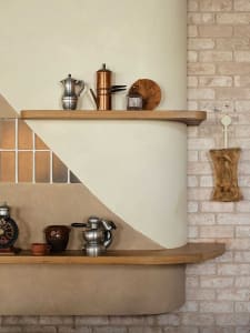 A kitchen area with a wooden countertop featuring various items, including cups, bottles, and bowls, in a cozy and functional space