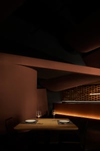 Dining area with wooden furniture, brick walls, and wine glasses, conveying a warm and inviting atmosphere