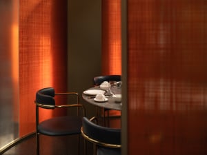 Cozy dining area with a wooden table surrounded by chairs, featuring cups, bowls, wine glasses, spoons, and knives