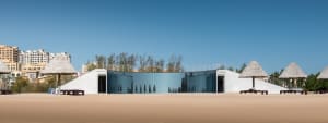A modern house with a glass wall reflecting trees and surrounding landscape, built with concrete and featuring a sleek and contemporary design