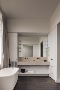 A modern bathroom with a white bathtub and two sinks, a mirror above the sink area, and a clean and simple design