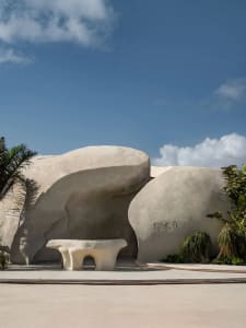 A serene landscape with a large white rock formation and a concrete bench in front, inviting visitors to sit and enjoy the view