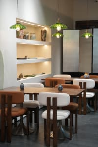 Modern restaurant interior with wooden tables and chairs, white walls, and brown wood accents, creating a warm and inviting atmosphere