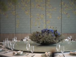 Elegant dining area with a round table, flowers, wine glasses, and fine china