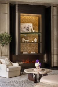 Cozy living room with a fireplace, two couches, a chair, and a potted plant, with warm lighting and a sense of evening atmosphere
