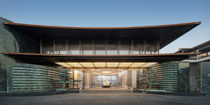 A modern building with a circular shape and a large glass wall featuring a fireplace, surrounded by natural light and a bright atmosphere