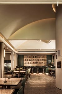Inviting restaurant interior with a bar, dining tables, and potted plants, creating a comfortable atmosphere for patrons