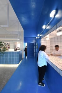 A bright and inviting hotel lobby with blue walls and floor, featuring a large open area with people socializing