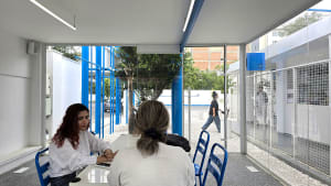 a cozy cafe with two women dining and potted plants scattered throughout